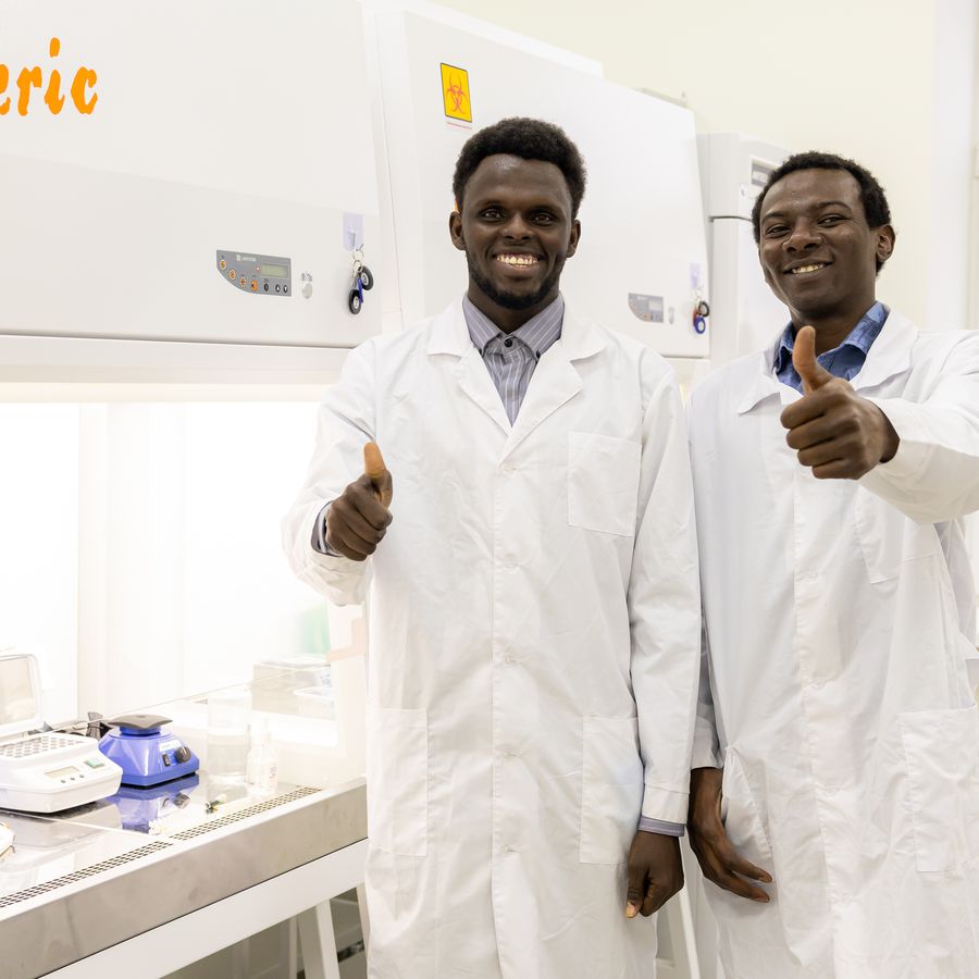 Two students in lab coats giving a thumbs-up