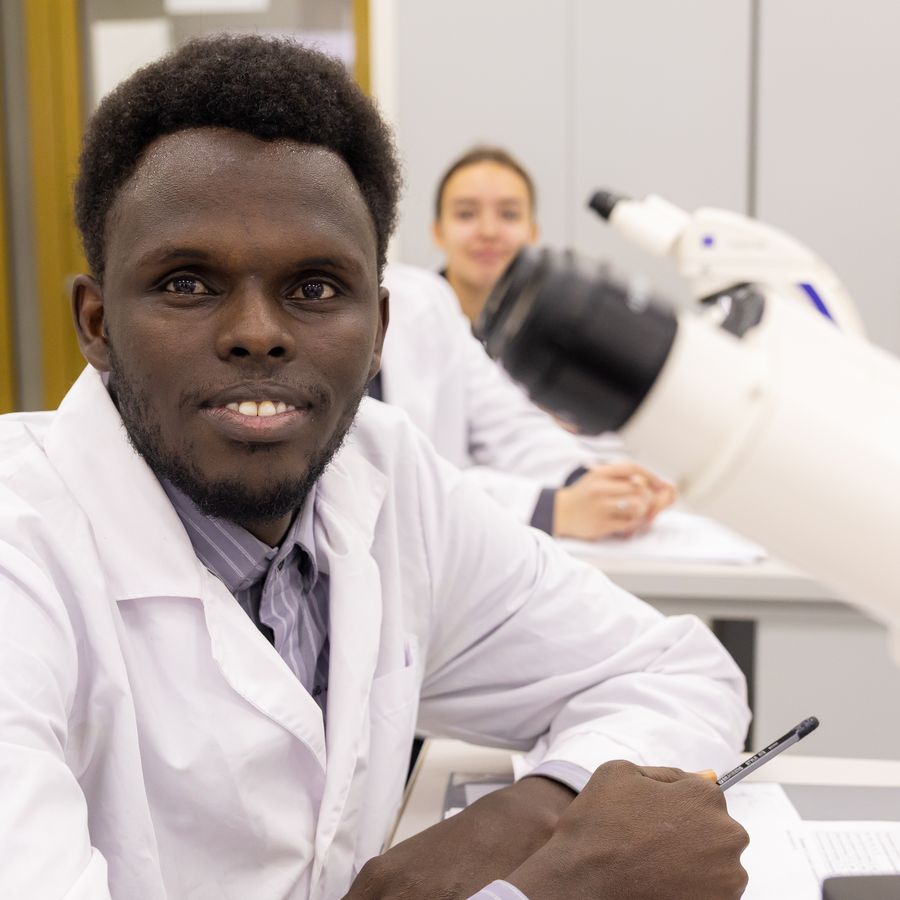 A smiling student at a microscope