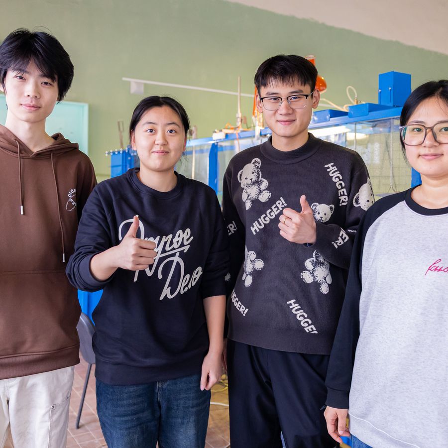 International students in an engineering laboratory giving a thumbs-up