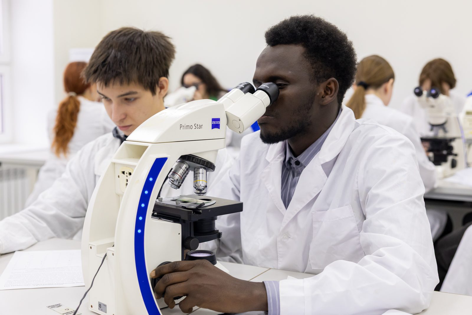 An international student at a microscope during a practical class with Russian classmates
